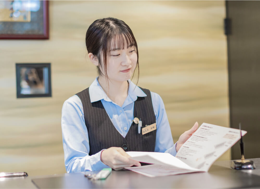 フロントで手続きを行う女性スタッフ（受付業務）