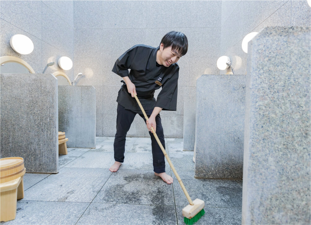浴場を清掃する男性スタッフ（清掃業務）