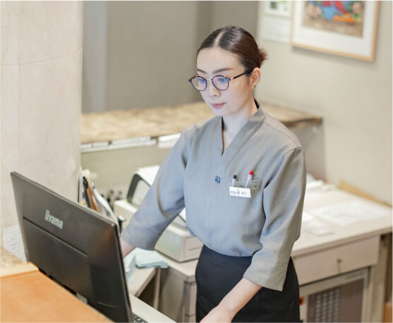 フロントでPC作業をする女性スタッフ