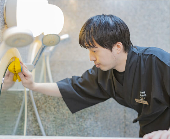 浴場設備を清掃する男性スタッフ